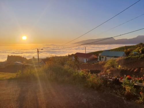 Vue du lever de soleil sur le Case Vi D'O BnB à La Plaine des Cafres avec vallée brouillarde et maisons à l'aube