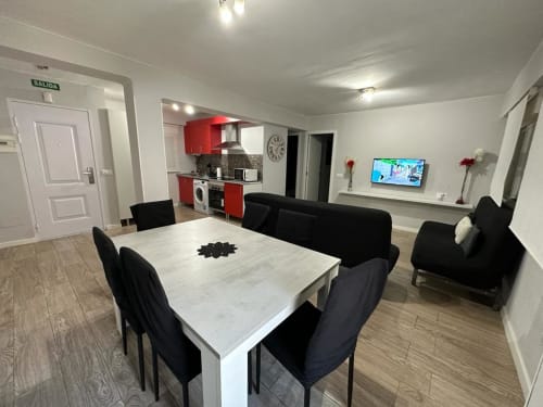 Apartamento moderno en Mérida con comedor, sillas negras, cocina roja, sofá negro y televisor