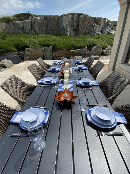 Outdoor dining table set for guests at Seabrook Lodge in Clifden, overlooking dramatic coastal cliffs