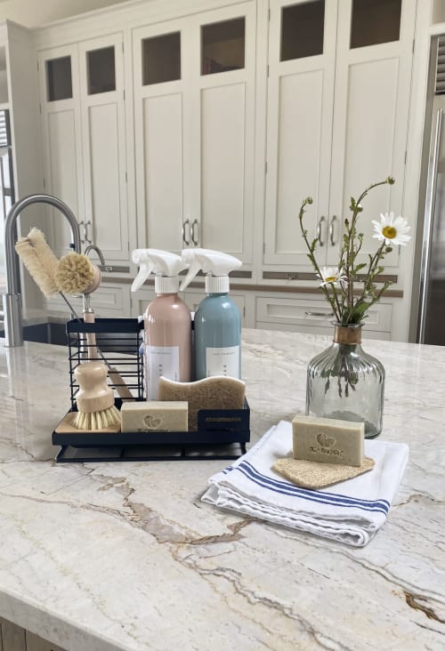 Luxury bathroom counter at Seabrook Lodge with marble, cleaning supplies, soap, flowers, and white cabinetry