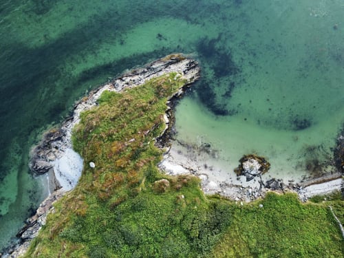 Aerial view of moss-covered rocky coastline with turquoise waters near Seabrook Lodge, Clifden, Galway