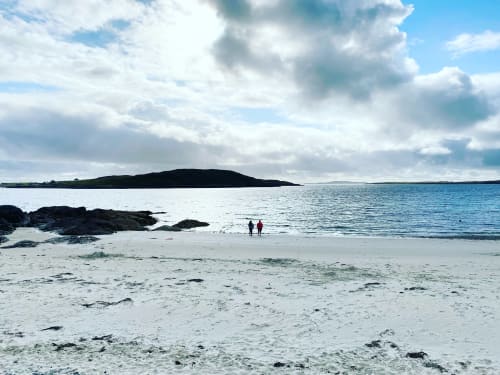 Scenic beach at Seabrook Lodge in Clifden, Galway with sandy shore, dark island, and visitors by turquoise waters