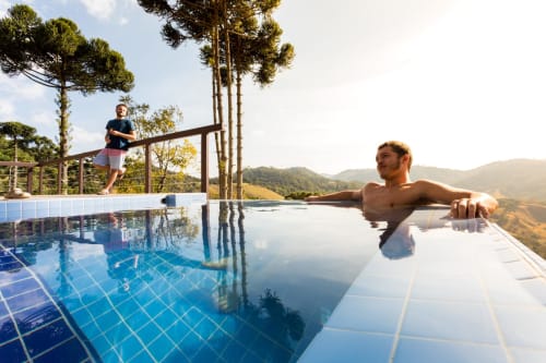 Homem relaxando em piscina de borda infinita da villa Paraíso nas Montanhas com vistas das montanhas em Campos do Jordão, Brasil
