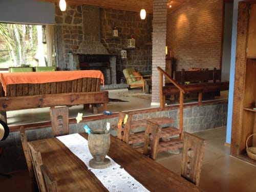 Interior rústico da villa Paraíso nas Montanhas com móveis de madeira, lareira de pedra e vistas para as montanhas em Campos do Jordão