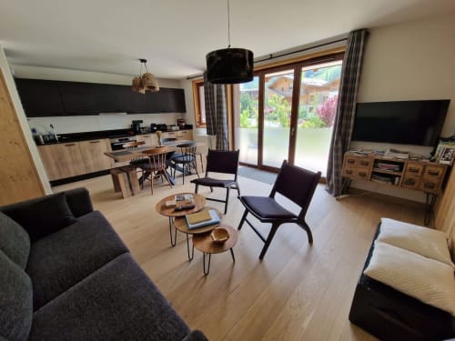 Modern open-plan living area at Serre Chevalier Cristal Lodge with kitchen, dining table, seating, and garden views in