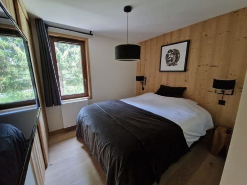 Modern bedroom at Serre Chevalier Cristal Lodge with wood paneling, black pendant light, and mountain views through large