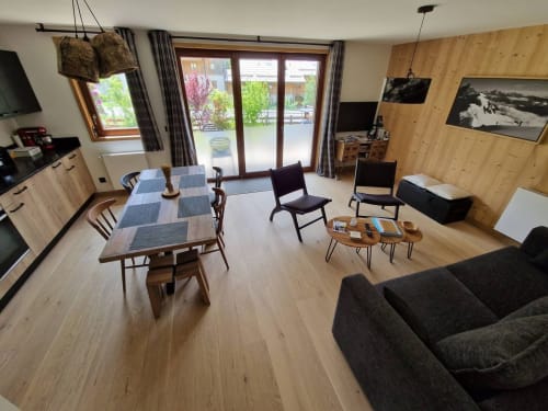 Spacious Serre Chevalier mountain apartment with dining table, living area, wood paneling, and terrace access in