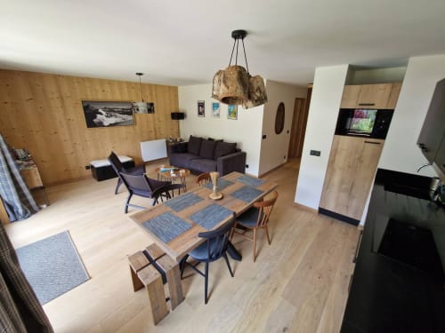 Modern open-plan apartment at Serre Chevalier with wooden dining table, dark seating area, and mountain lodge design