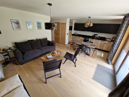 Modern open-plan living area with dark sofa, dining table, and kitchen at Serre Chevalier Cristal Lodge apartment in