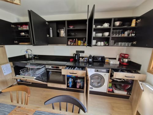 Modern kitchen in Serre Chevalier apartment with black cabinets, washer-dryer, and dining area