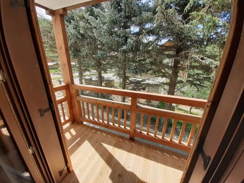 Wooden balcony with railing overlooking evergreen forest at Serre Chevalier Cristal Lodge, Saint-Chaffrey