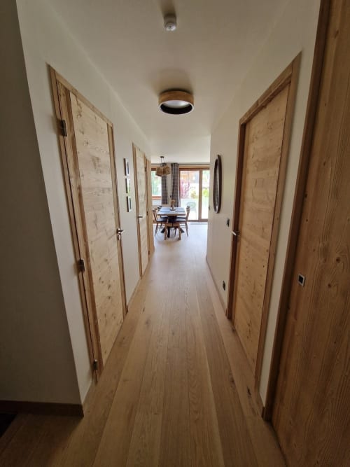 Modern hallway with wooden doors and flooring at Serre Chevalier Cristal Lodge in Saint-Chaffrey