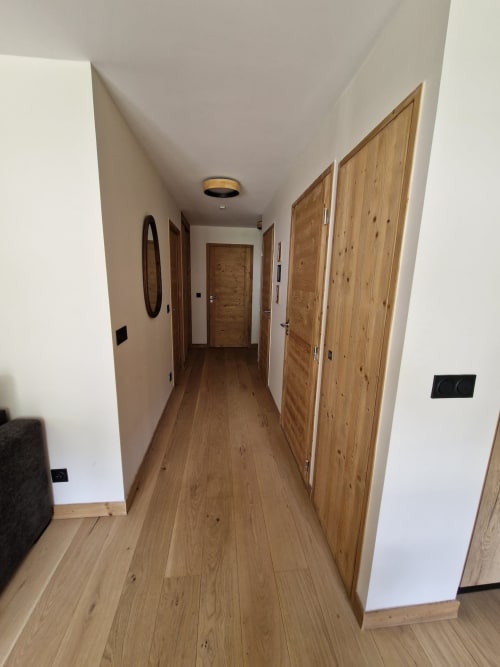 Modern hallway with wooden doors and flooring at Serre Chevalier Cristal Lodge, Saint-Chaffrey