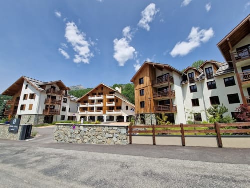 Serre Chevalier Cristal Lodge à Saint-Chaffrey : chalets alpins aux façades blanches et bois avec vue panoramique sur les montagnes