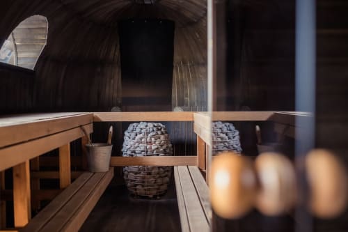 Intérieur du sauna du Serre Chevalier Cristal Lodge avec bancs en bois, pierres chauffantes et seau à Saint-Chaffrey