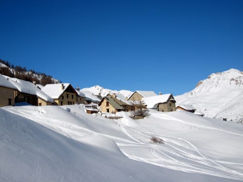 Villaggio alpino innevato con edifici in pietra tradizionali immerso nelle montagne francesi vicino a Serre Chevalier.