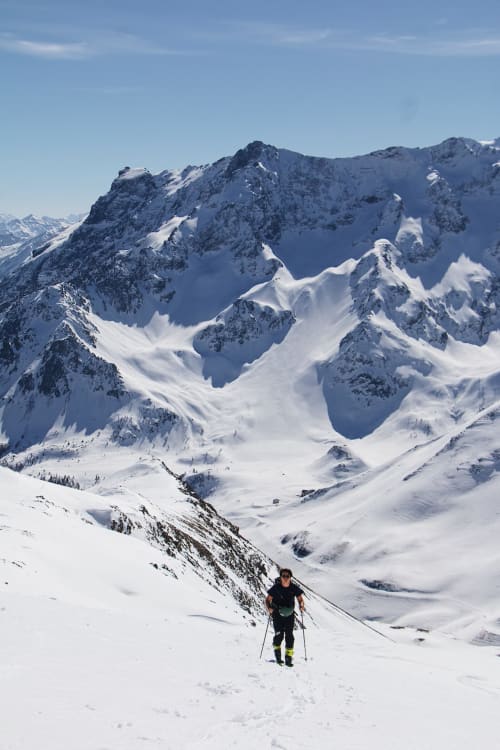 Sciatore che sale i picchi alpini innevati vicino al Serre Chevalier Cristal Lodge a Saint-Chaffrey, Francia