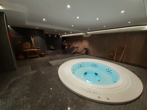 Modern spa area at Serre Chevalier Cristal Lodge with illuminated jacuzzi, lounge chairs, and ambient lighting