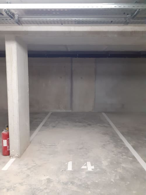 Empty covered parking space 14 at Serre Chevalier Cristal Lodge with concrete floor and fire extinguisher