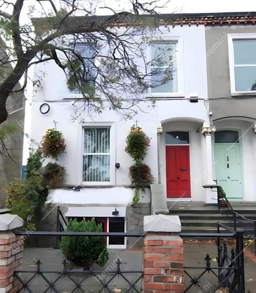 White townhouse with red door on Eglinton Road, Bray. Charming B&B exterior with hanging baskets and traditional