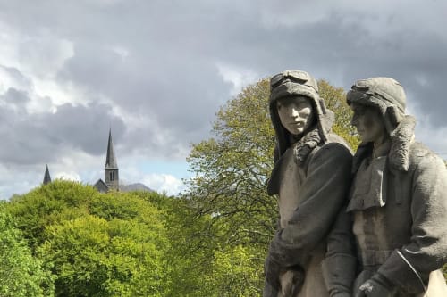 Stone statues overlooking Clifden with church spires and green trees, near Seabrook Lodge in Co. Galway, Ireland