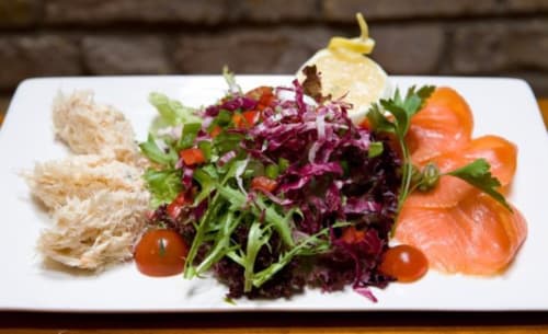 Elegant plated salad with shredded chicken, mixed greens, purple cabbage, cherry tomatoes, and smoked salmon at Seabrook