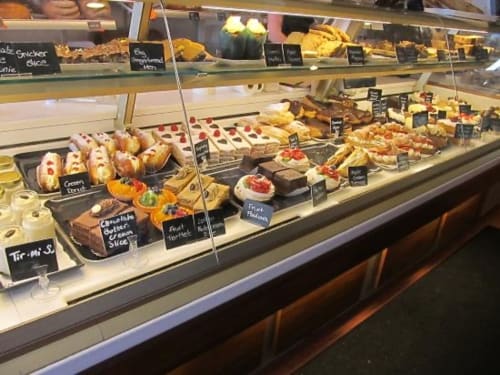 Bakery display case at Seabrook Lodge in Clifden featuring pastries, cakes, and desserts with chalkboard labels