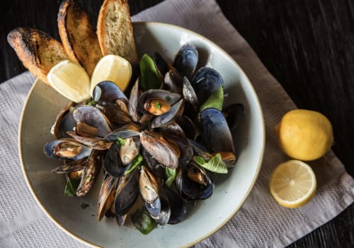 Elegant mussels dish at Seabrook Lodge in Clifden, Galway, with crusty bread and fresh lemon wedges on white plate