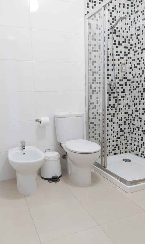 Banheiro moderno em Ó da Casa em Peniche com louças brancas, azulejos mosaico preto e cinza, e duche aberta