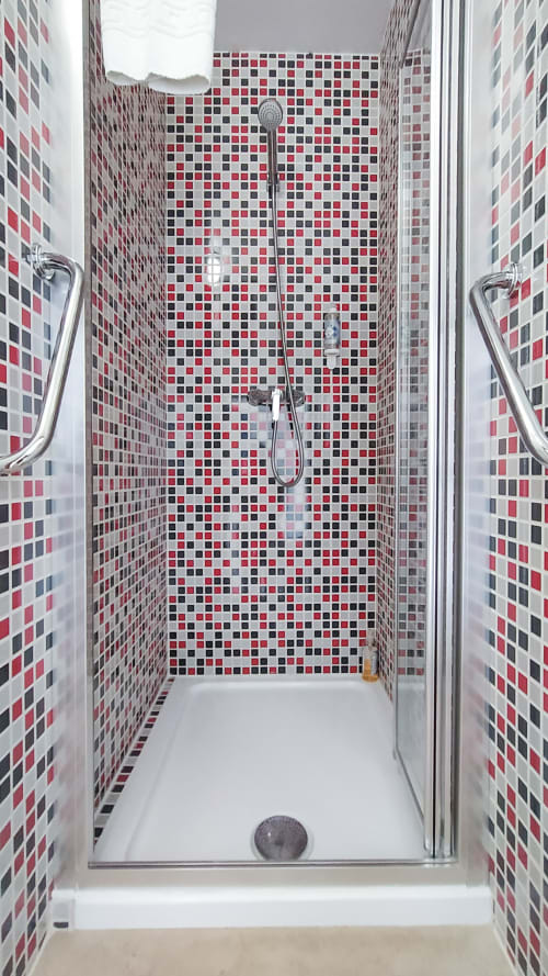 Boxe de banho moderno com azulejos de mosaico vermelho, preto e branco na pousada Ó da Casa em Peniche