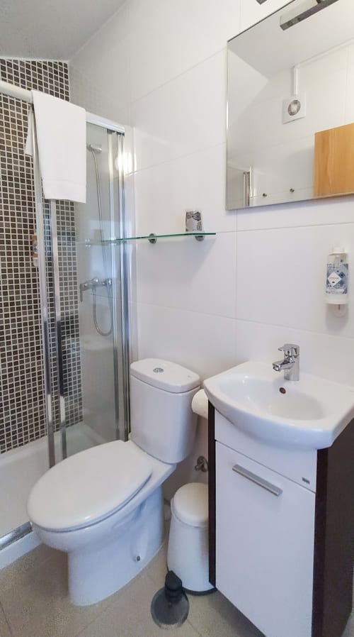 Banheiro moderno da Ó da Casa B&B em Peniche com louças brancas, chuveiro revestido em mosaico, pia e vaso sanitário