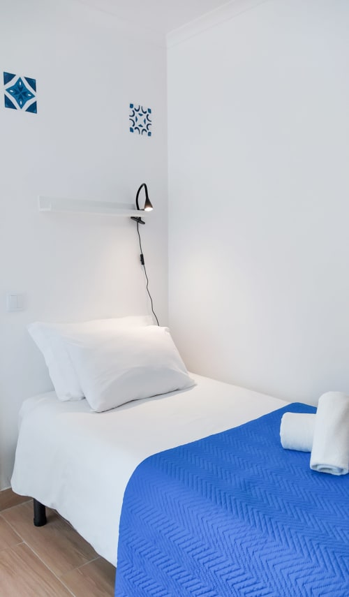 Quarto Bordalo em Ó da Casa em Peniche com roupa de cama azul e branca, travesseiros brancos e decoração de parede geométrica azul