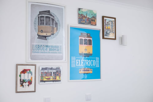 Galeria de obras de arte e ilustrações de bondes vintage de Lisboa expostas em parede branca na sala Elétrico em Ó da Casa, Peniche