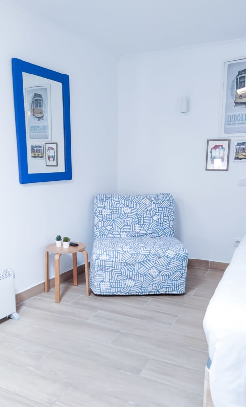 Obra de arte de bonde com moldura azul acima de cadeira estampada no quarto de hóspedes Ó da Casa, Peniche Portugal