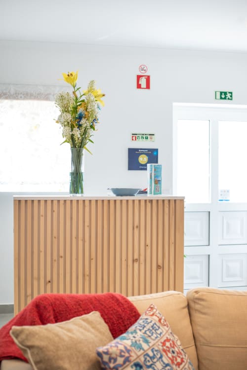 Accueil chaleureux du Ó da Casa BnB à Peniche avec bureau en bois, fleurs et espace détente
