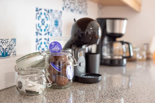 Station café à Ó da Casa avec machine à capsules, bocaux en verre et décoration portugaise