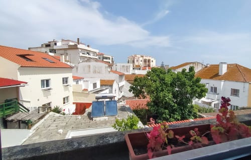 Vista da cidade de Peniche desde a pousada Ó da Casa com edifícios brancos, telhados de terracota e vegetação verde