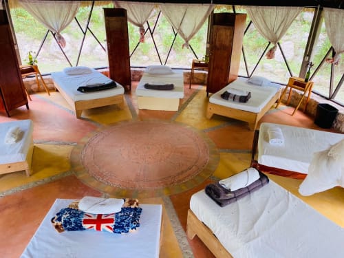 Dormitorio del hostal Cayuco Maya en Bacalar con camas de madera, ropa de cama blanca y vistas al jardín desde las ventanas