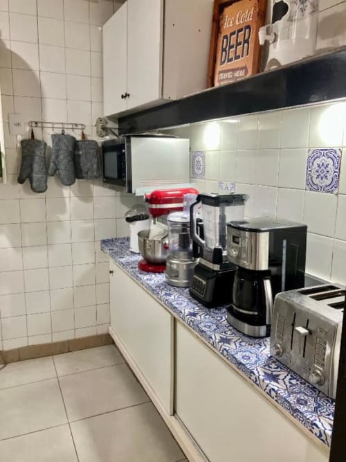 Cozinha do Hostel New Ipanema com eletrodomésticos, bancada estampada azul e paredes com azulejos brancos no Rio de Janeiro