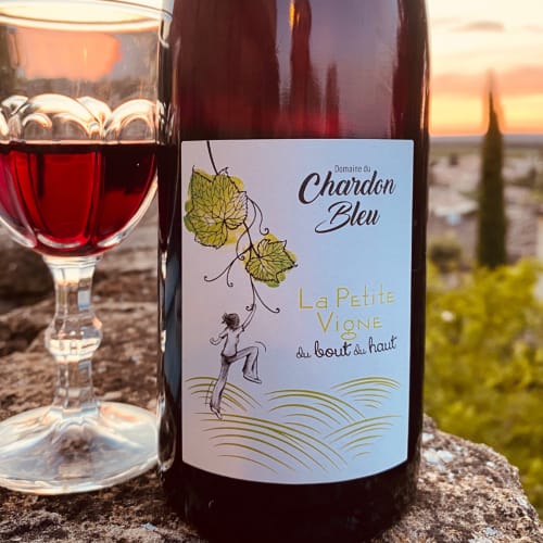 Verre de vin rouge avec la bouteille Chardon Bleu au coucher de soleil à Grignan, France