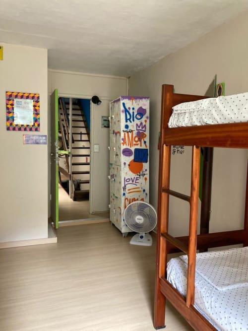 Quarto Carioca do Hostel New Ipanema, Rio de Janeiro, com beliche de madeira, lençóis brancos e ventilador