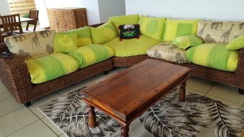 Salon lumineux avec canapé d'angle en rotin vert citron, table basse en bois et tapis à motifs animaliers à la Case Vi D'O B&B