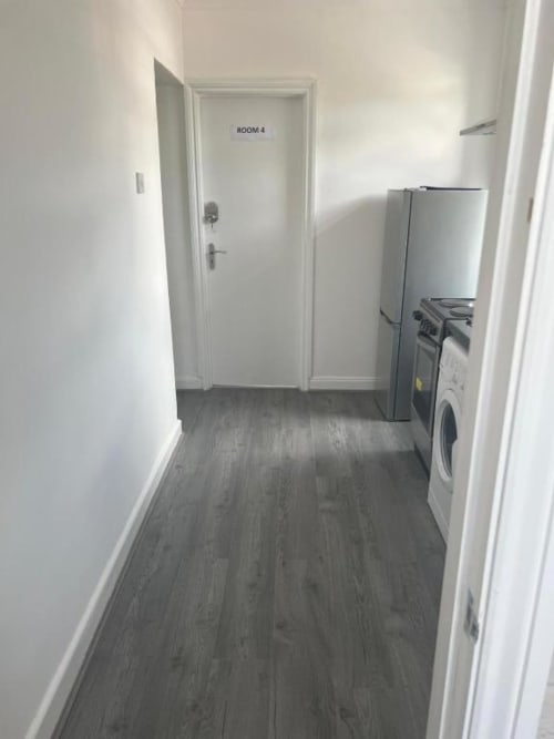 Hotel corridor at Starlet Property London with Room 4 door, washing machine, refrigerator, and gray wood flooring
