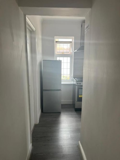 Modern kitchen hallway at Starlet Property London hotel with stainless steel refrigerator, stove, and window with natural