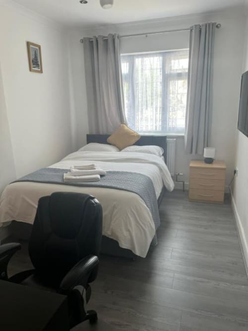 Modern bedroom at Starlet Property hotel in London with single bed, desk, chair, and large window with grey curtains
