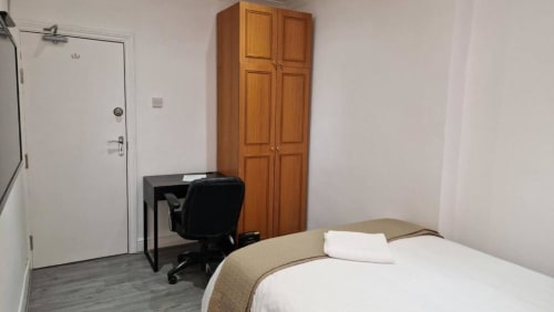 Modern hotel room at Starlet Property London with bed, desk, wooden wardrobe, and en-suite bathroom entrance