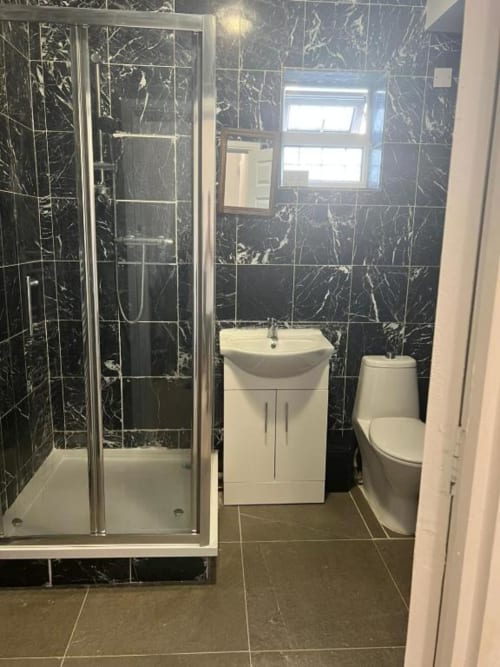 Modern black marble bathroom at Starlet Property London with shower, white vanity sink, and toilet