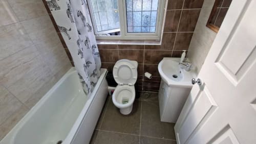 Bathroom in Room 4 at Starlet Property London, with toilet, sink, bathtub, and shower with zebra curtain