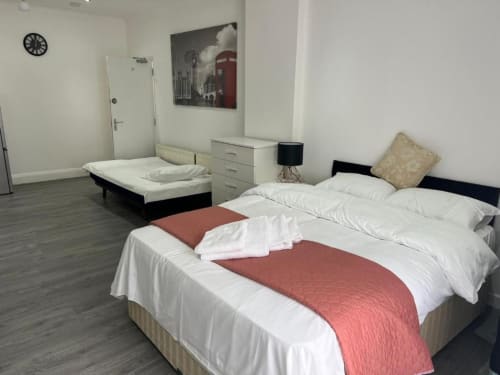 Starlet Property Studio 1 in London: modern bedroom with double bed, sofa bed, white linens, red runner, and ensuite