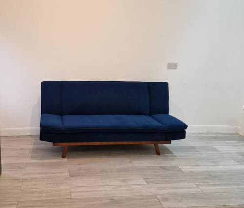 Navy blue sofa bed in Studio 1 apartment at Starlet Property London, featuring wooden legs and modern furnishings